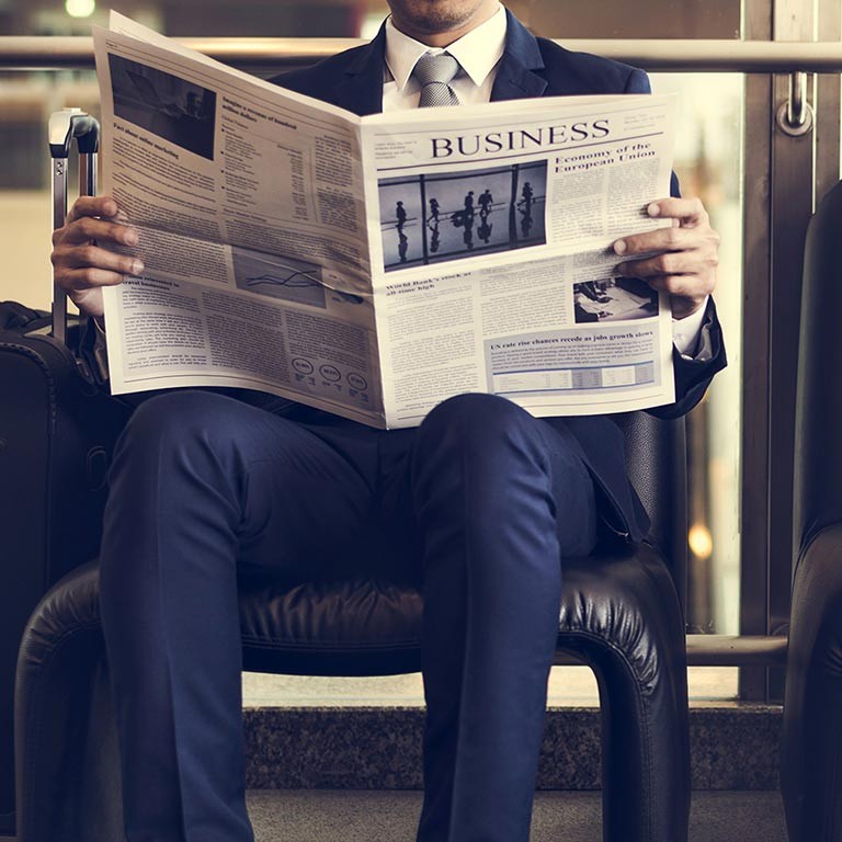 İş adam oturmuş ve bir gazetede haber okuma