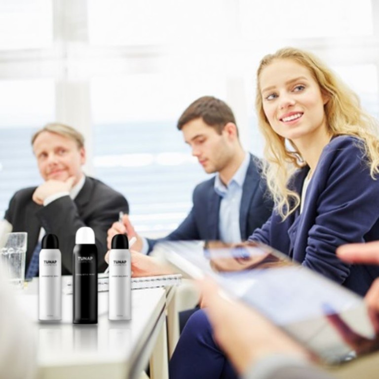 Smiling lady sitting at a table with aerosol spray cans