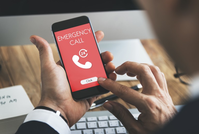 Zehir Kontrol Merkezi Acil arama numarasını gösteren kırmızı beyaz renkli ekranı olan bir akıllı telefonu tutan el