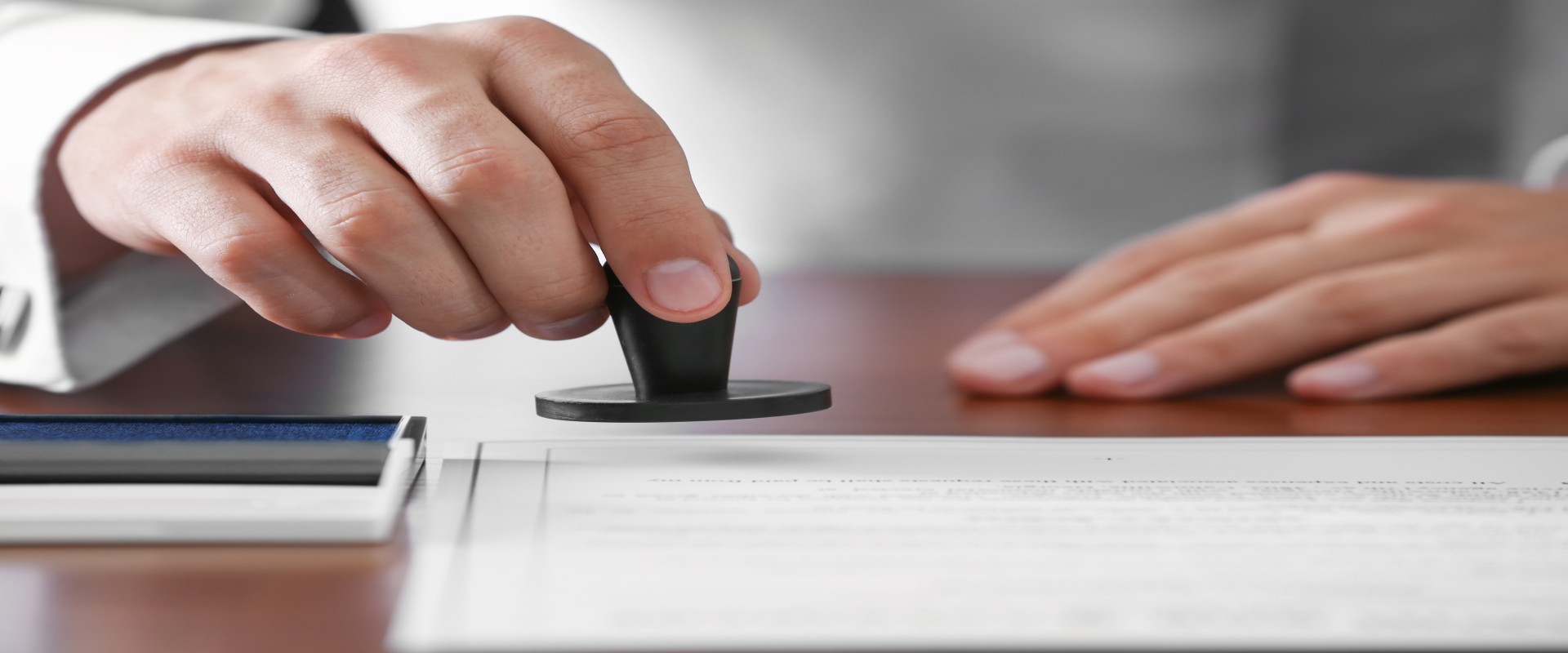 Close-up of a hand that is lowering a stamp onto a piece of paper