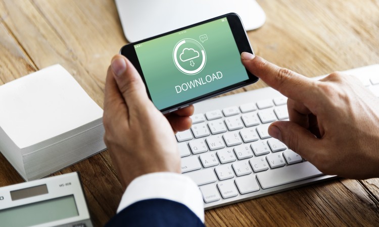 Man holding a mobile phone above keyboard